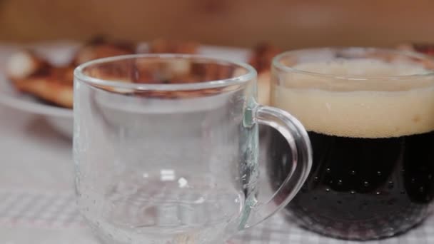 Bier wordt in glazen op tafel gegoten met vlees. — Stockvideo