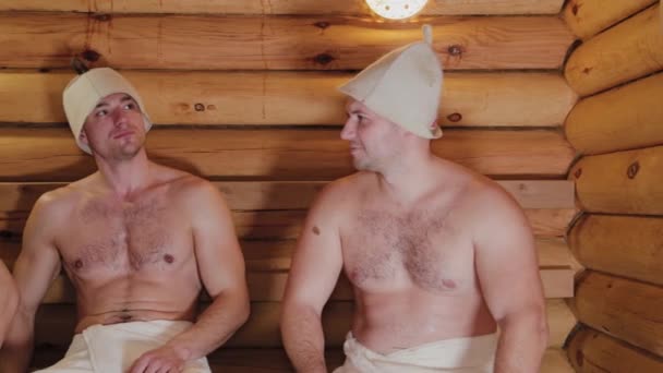 Guapos hombres físicamente desarrollados se elevan en la sauna . — Vídeo de stock