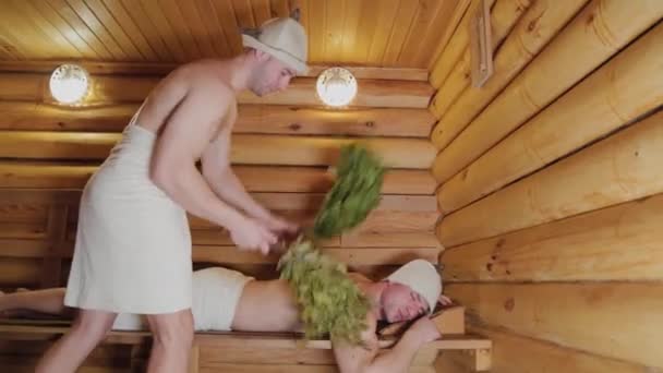 Uomini atletici che volano in una sauna con scope . — Video Stock