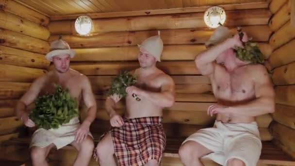 Sportowcy szybujący w saunie z miotłami. — Wideo stockowe