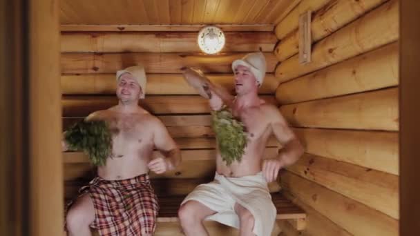 Athletic men soaring in a sauna with brooms. — 비디오