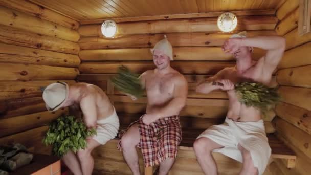 Atletische mannen zweven in een sauna met bezems. — Stockvideo