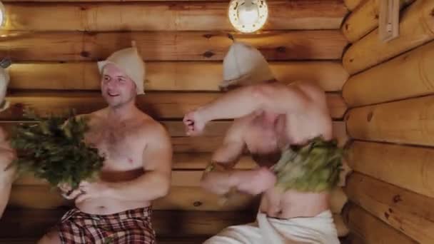Homens atléticos voando em uma sauna com vassouras . — Vídeo de Stock