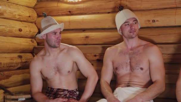 Guapos hombres físicamente desarrollados se elevan en la sauna . — Vídeo de stock