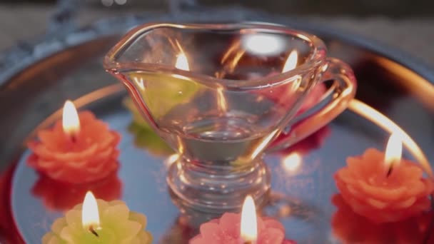 Masseur gießt Massageöl in einen Glasbehälter. Kerzen brennen herum. — Stockvideo