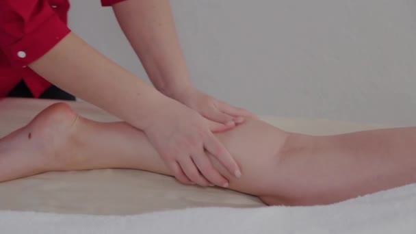 Weibliche Massagetherapeutin massiert Klienten Beine. — Stockvideo