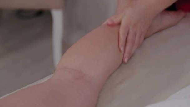 Weibliche Massagetherapeutin massiert Klienten Beine. — Stockvideo