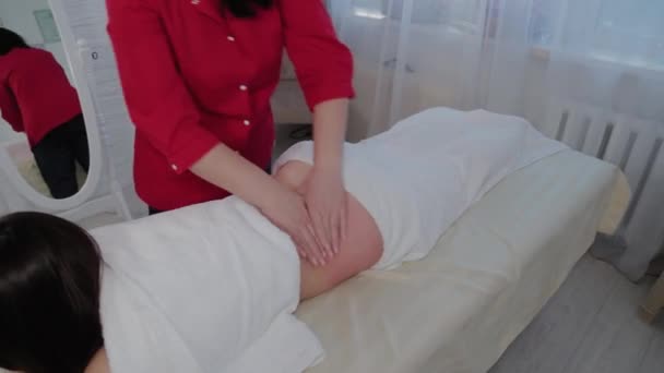 Woman massage therapist doing massage on the sides of a young girl in a massage parlor. — Stock Video