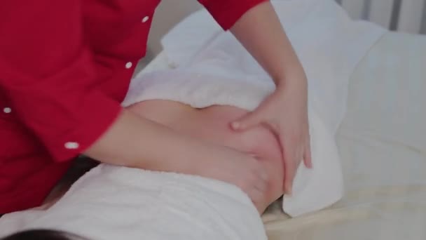 Woman massage therapist doing massage on the sides of a young girl in a massage parlor. — Stok video