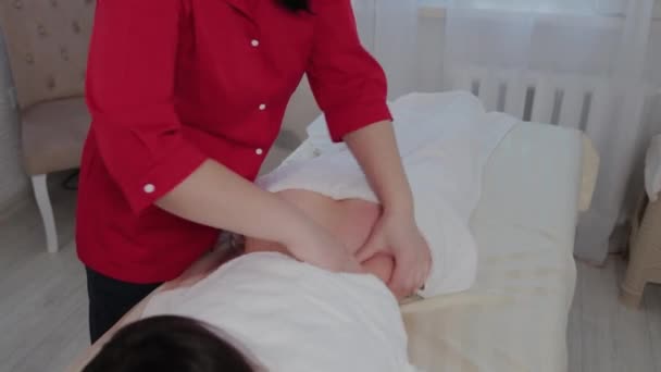 Mujer terapeuta de masaje haciendo masaje en los lados de una chica joven en un salón de masajes . — Vídeo de stock