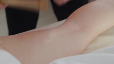 Masaj salonundaki müşteriye bambu çubuklarıyla masaj yapan kadın masaj terapisti..