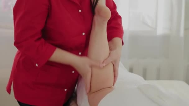 Weibliche Massagetherapeutin massiert Klienten Beine. — Stockvideo