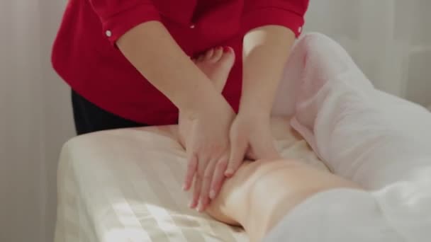 Female massage therapist massaging clients legs. — 비디오