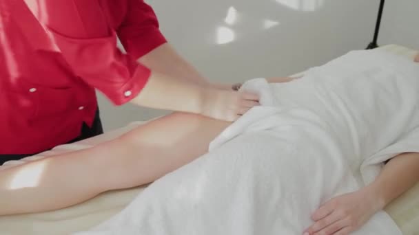 Weibliche Massagetherapeutin massiert Klienten Beine. — Stockvideo