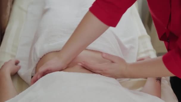 Massagetherapeutin massiert einem jungen Mädchen den Bauch. — Stockvideo