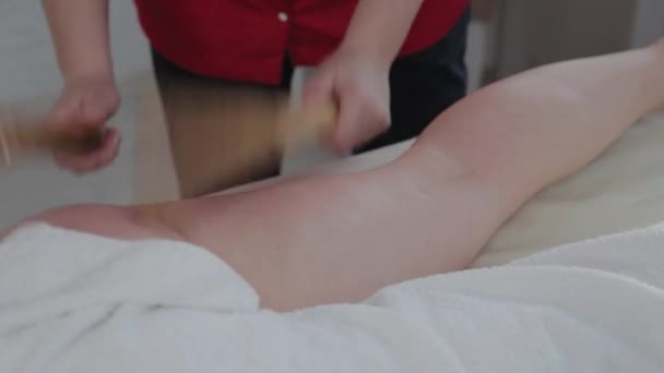 Massagista feminina fazendo massagem com paus de bambu para o cliente em sala de massagem . — Vídeo de Stock