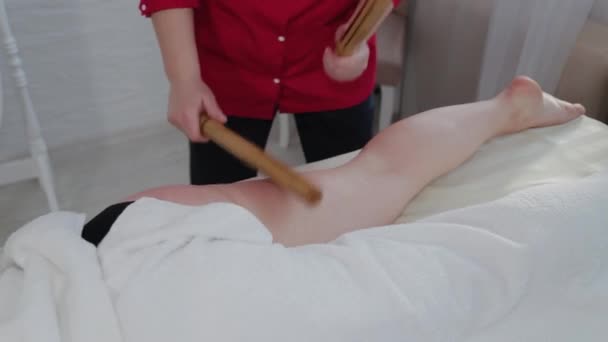 Massagista feminina fazendo massagem com paus de bambu para o cliente em sala de massagem . — Vídeo de Stock