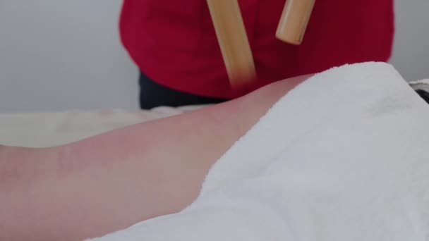 Massothérapeute féminine faisant un massage avec des bâtons de bambou au client dans le salon de massage . — Video