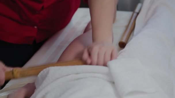 Female massage therapist doing massage with bamboo sticks to client in massage parlor. — 비디오