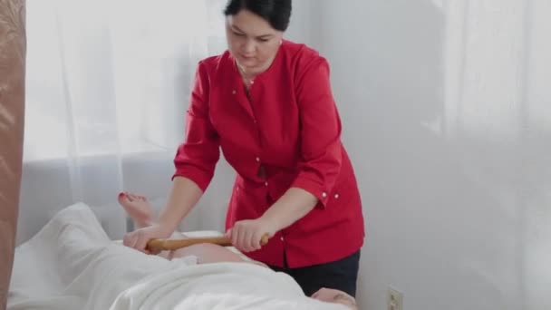 Massagista feminina fazendo massagem com paus de bambu para o cliente em sala de massagem . — Vídeo de Stock