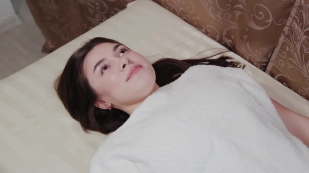 Vacker ung flicka på en soffa i en skönhetssalong. — Stockvideo