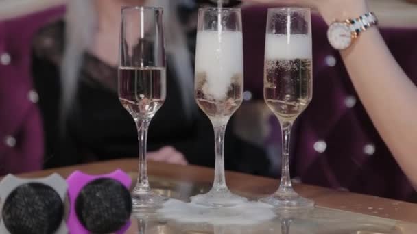 Meisje giet champagne in glazen op een tafel met een microfoon. — Stockvideo