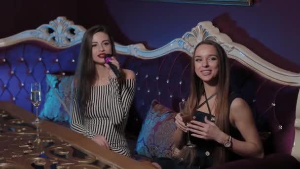 Güzel genç kızlar bir kanepede karaoke kulübünde şarkı söylüyorlar.. — Stok video