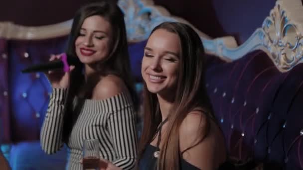 Krásné mladé dívky zpívající v karaoke klubu na pohovce. — Stock video