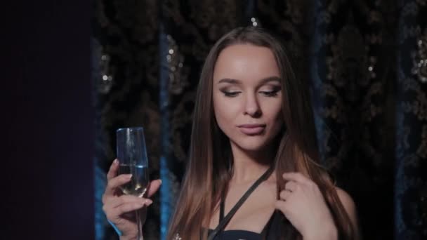 Mooie jonge vrouw met een glas champagne in een restaurant interieur. — Stockvideo