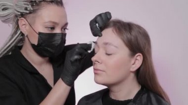 Kadın usta müşteriye kaşlarını boyuyor..