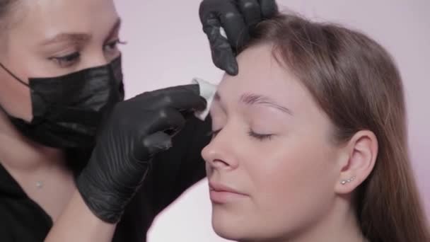Mujer maestro pinta las cejas al cliente . — Vídeos de Stock