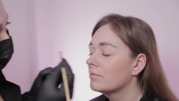 Woman master paints eyebrows to client. — Stock Video