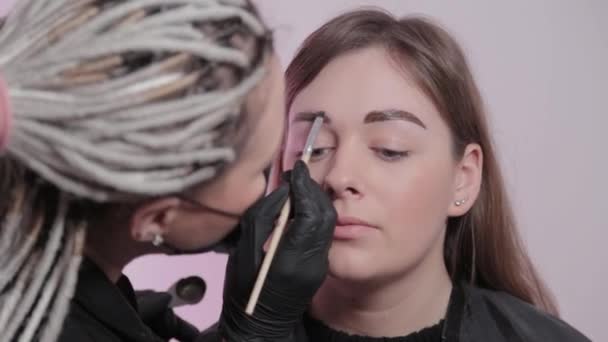 Kvinna mästare målar ögonbryn till kunden. — Stockvideo