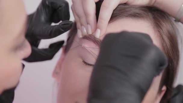 Artista de maquillaje profesional arrancando cejas al cliente en el salón de belleza . — Vídeo de stock