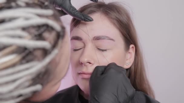 Maquilleur professionnel arrachant les sourcils au client au salon de beauté .