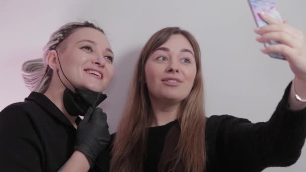 Kvinna make-up artist och klient flicka ta en selfie i en skönhetssalong efter ingreppet. — Stockvideo