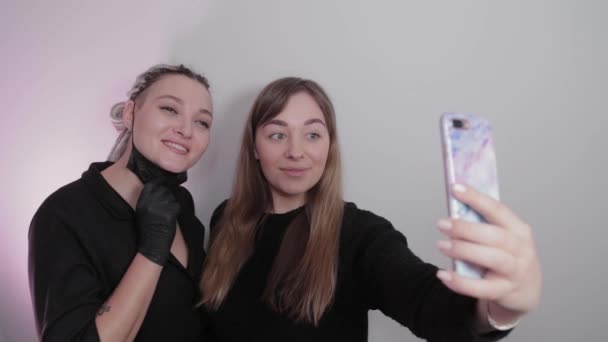 Vrouw make-up kunstenaar en klant meisje nemen een selfie in een schoonheidssalon na de procedure. — Stockvideo