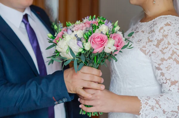 Giovane e felice sposa e lo sposo in possesso di un bouquet di nozze nelle loro mani . — Foto Stock