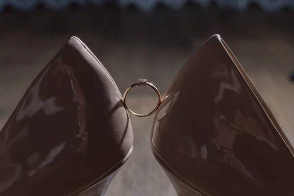 Sapatos de mulheres de casamento com um anel de casamento iluminado pela luz da foto . — Fotografia de Stock