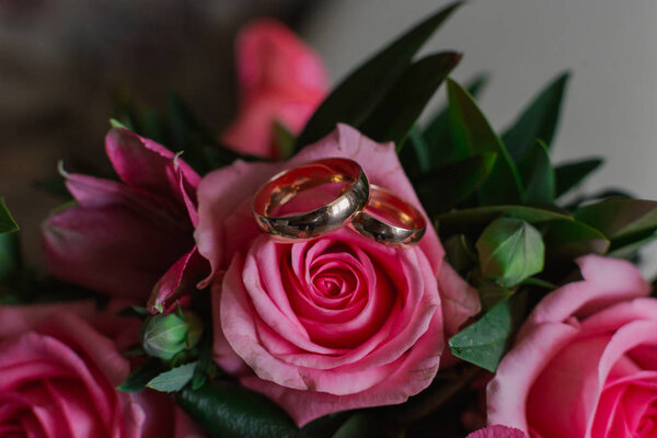 New wedding rings next to the brides bouquet.