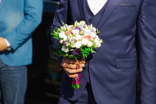 Bella giovane sposo elegante con un bouquet da sposa in mano . — Foto Stock
