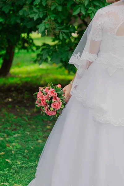 Jonge gelukkige bruid met een bruiloft boeket door een boeket. — Stockfoto