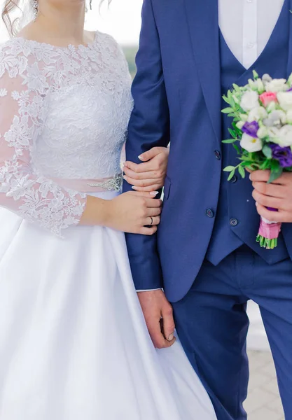 Young and happy bride and groom holding a wedding bouquet in their hands. — 图库照片