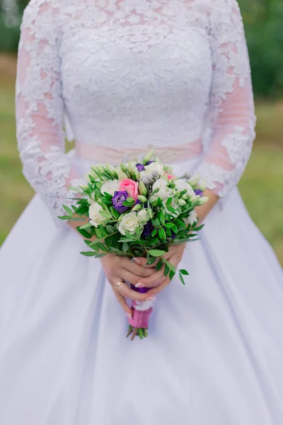 Jonge gelukkige bruid met een bruiloft boeket door een boeket. — Stockfoto