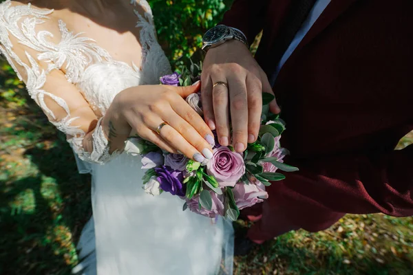Beautiful hands with wedding rings of the newlyweds on a bouquet. — ストック写真