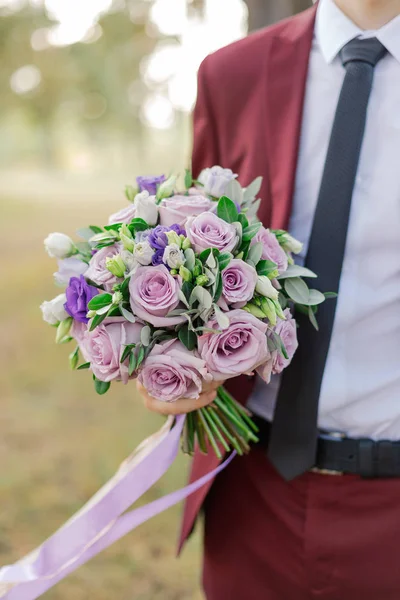 Bella giovane sposo elegante con un bouquet da sposa in mano . — Foto Stock
