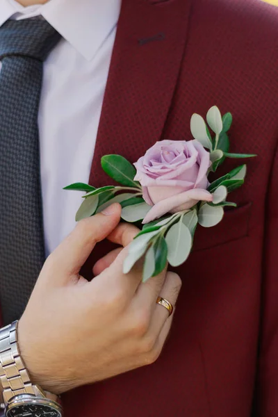 Lo sposo giovane elegante raddrizza un boutonniere su una giacca . — Foto Stock