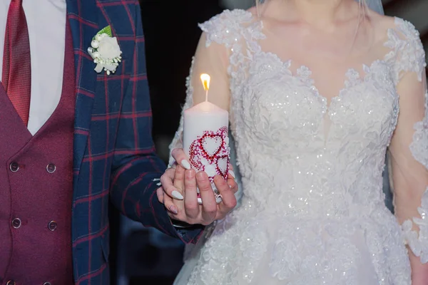 Beautiful newlyweds light a candle at a wedding celebration. — Stok fotoğraf