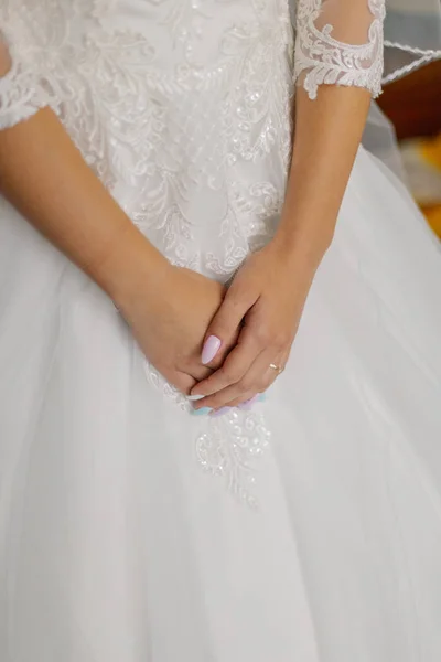Jonge bruid handen op een trouwjurk. — Stockfoto