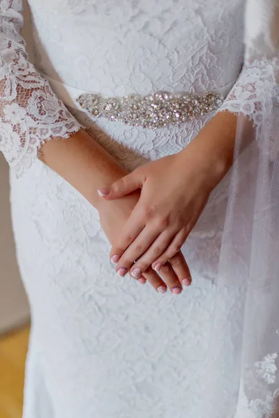 Jeune mariée mains sur une robe de mariée . — Photo